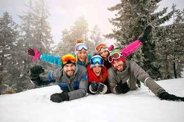 Wall Mural - friends on winter holidays - Skiers lying on snow and having fun