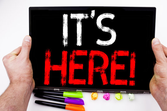 It's Here text written on tablet, computer in the office with marker, pen, stationery. Business concept for advertisement white background with copy space