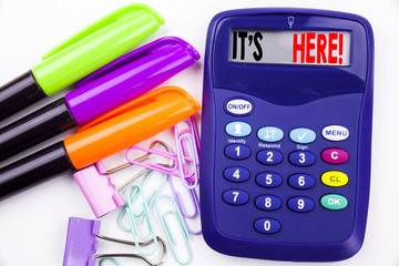 Poster - Writing word It's Here text in the office with surroundings such as marker, pen writing on calculator. Business concept for advertisement white background with copy space