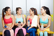 © pressmaster - Row of sporty girls in activewear having talk while having short break after gym