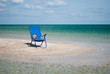 Blue beach chair and stylish white hat on the shore of the blue sea island of sand in the water blue sky white clouds sea wave beautiful landscape summer vacation beach sand weekend rest