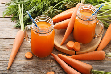 Canvas Print - Fresh carrot juice in glass jars on grey wooden background