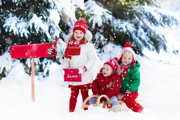 Wall Mural - Children with letter to Santa at Christmas mail box in snow