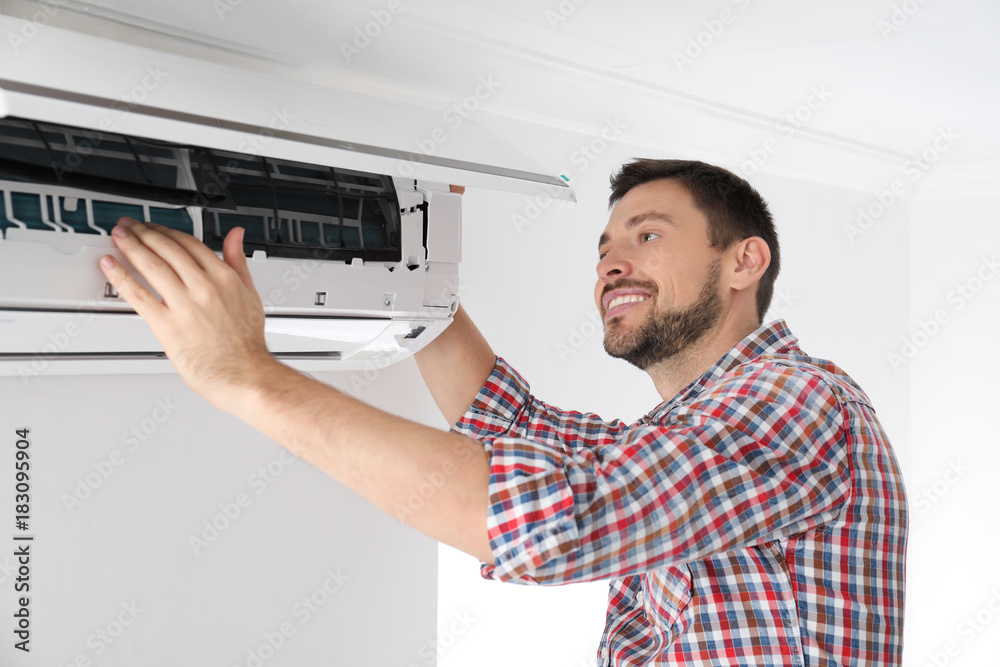 Man cleaning air conditioner indoors