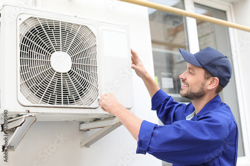 Fotografía Male technician repairing air conditioner outdoors