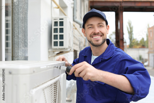 Fotografía Male technician repairing air conditioner outdoors