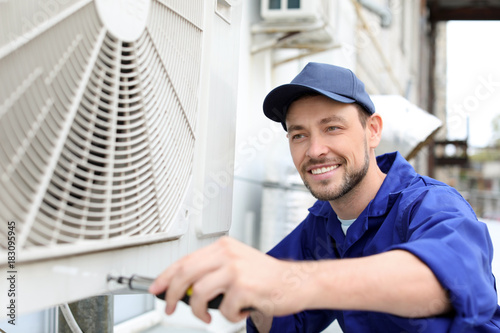 Cuadros en Lienzo Male technician repairing air conditioner outdoors