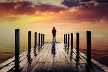 Lonely Man Standing On A Wooden Pier During Sunset Facing Mountain