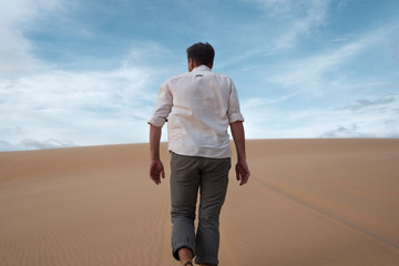 Caucasian young man going straight on his way on sandy desert