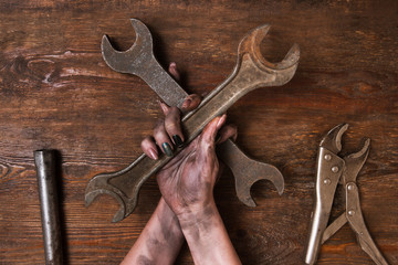 Two crossed spanners on wooden background in woman's hands. Service repair and maintenance concept