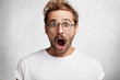 © WHstudio Leushin N - Emotional bugged eyed stylish man keeps mouth widely opened being greatly surprised to find out about reduction, didn`t expect such bad news, looks terrified and shocked, poses in white studio