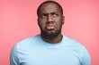 © wayhome.studio  - Displeased black man curves lips, being deep in thoughts, looks upwards, remembers unpleasant moments in life, poses against pink background. Negative emotions and facial expressions concept