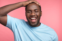 Joyful Glad Black Cheerful Black Man Being Satisfied With Results Of Work, Closes Eyes With Happiness, Keeps Hand On Head, Isolated Over Pink Background. African American Male Has Good Mood.
