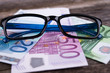 glasses frame with money on wooden ground