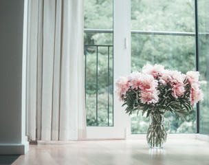 Wall Mural - Glorious pastel pink bouquet of peonies in glass jug on  floor by window.  Flowers in interior design. Cozy home.