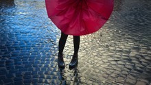 Girl With Red Umbrella On The  Rough Cobblestone Pavement After The Rain.