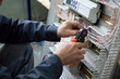 © Kuznietsov Dmitriy - Hands of electrician assembling industrial HVAC control cubicle in workshop. Close-up photo.