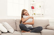 © Prostock-studio - Young smiling woman thinking on beige couch