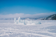 Ice Sculpture Castle Under A Big Blue Sky And Footprints On Snow. A Palace Under Large Blue Sky In The Middle Of Frozen Lake Baikal Covering With Snow. Footprints Lead To The Building.