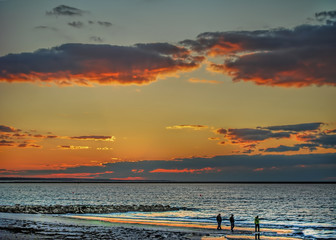 Ocean sunset with silhouette of people at water's edge