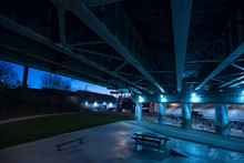 Gritty Dark Chicago Highway Bridge Underpass And City Street With Traffic And A Bench At Night.