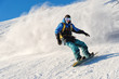 © yanik88 - Freeride snowboarder rolls on a snow-covered slope leaving behind a snow powder against the blue sky