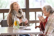 © Africa Studio - Senior woman and young caregiver drinking tea at table in cafe