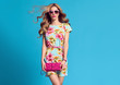 Fashion. Blond Woman in fashion pose. Young beauty Lady in Floral Dress Blowing lips. Trendy fashion Hairstyle, Glamour Pink Clutch. Playful Girl, Spring Summer Outfit
