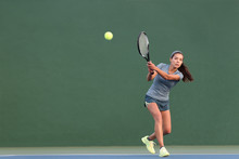 Tennis Playing Woman Hitting Ball On Green Hard Court. Asian Athlete Girl Returning Serve With Racket Wearing Skort And Shoes.