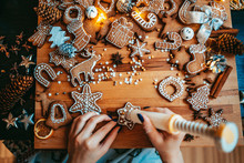 Woman Decorating Baked Gingerbread Christmas Cookies With Icing And Confectionery Mastic, View From Above. Festive Food, Family Culinary, Christmas And New Year Traditions Concept.