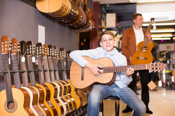 Male seller showing guitar to boy client