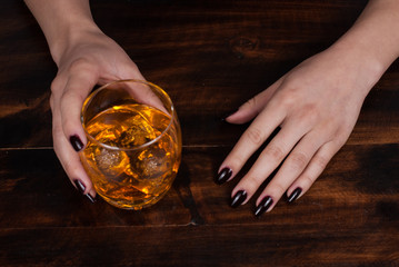 woman's hands with a glass with whiskey