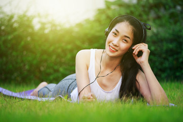 Sticker - woman listening to music with headphones and laying on a grass field