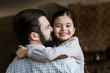 © LIGHTFIELD STUDIOS - cheerful father and daughter hugging and looking at camera at home
