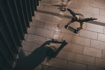 Wall Mural - high angle view of skateboarder in modern streetwear performing jump trick