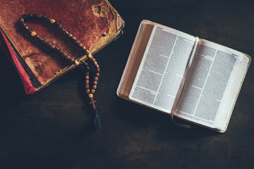 top view of open holy bible with rosary on table