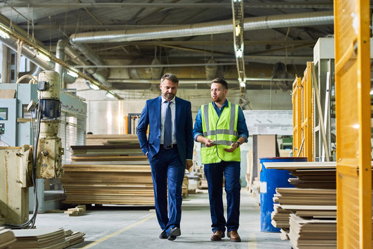 full length portrait of young workman giving tour of modern factory to handsome mature businessman d