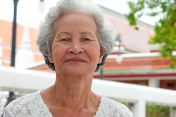 Older Asian women with grayish hair have smiling faces onTemple background