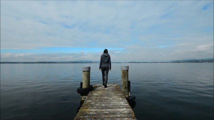 Sticker - The woman is walking on the pier. Lake Shore. Overcast