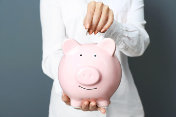 Poster - Young woman with piggy bank on color background