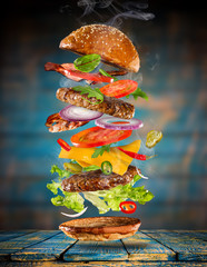 Wall Mural - Big tasty burger with flying ingredients.