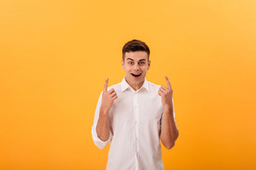 Surprised happy man in white shirt pointing up