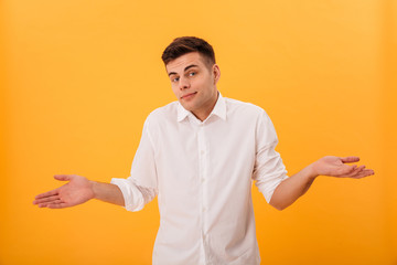 Confused man in white shirt shrugs his shoulder