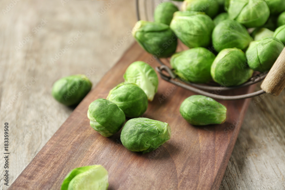 Basket with fresh scattered Brussels sprouts on wooden background