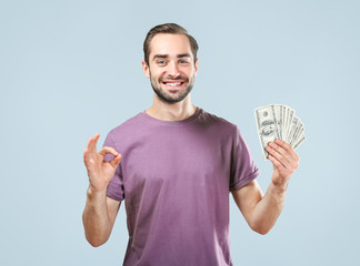 Sticker - Handsome man with dollar bills showing OK gesture, on light background