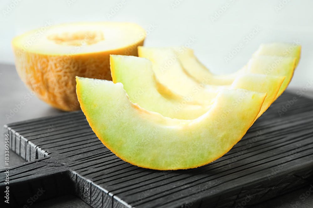 Wooden board with yummy melon slices on table