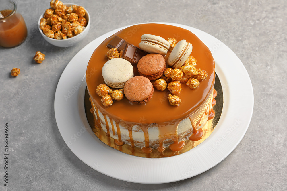Plate with delicious caramel cake on table