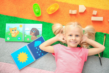 Canvas Print - Cute little girl with toys on color carpet in kindergarten