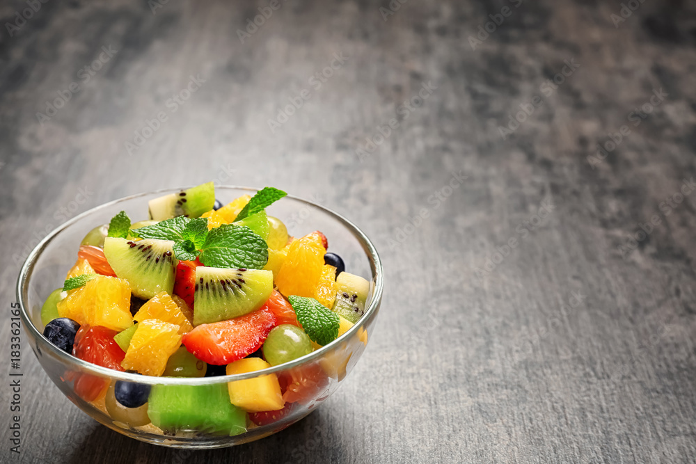 Bowl with delicious fruit salad on grey background