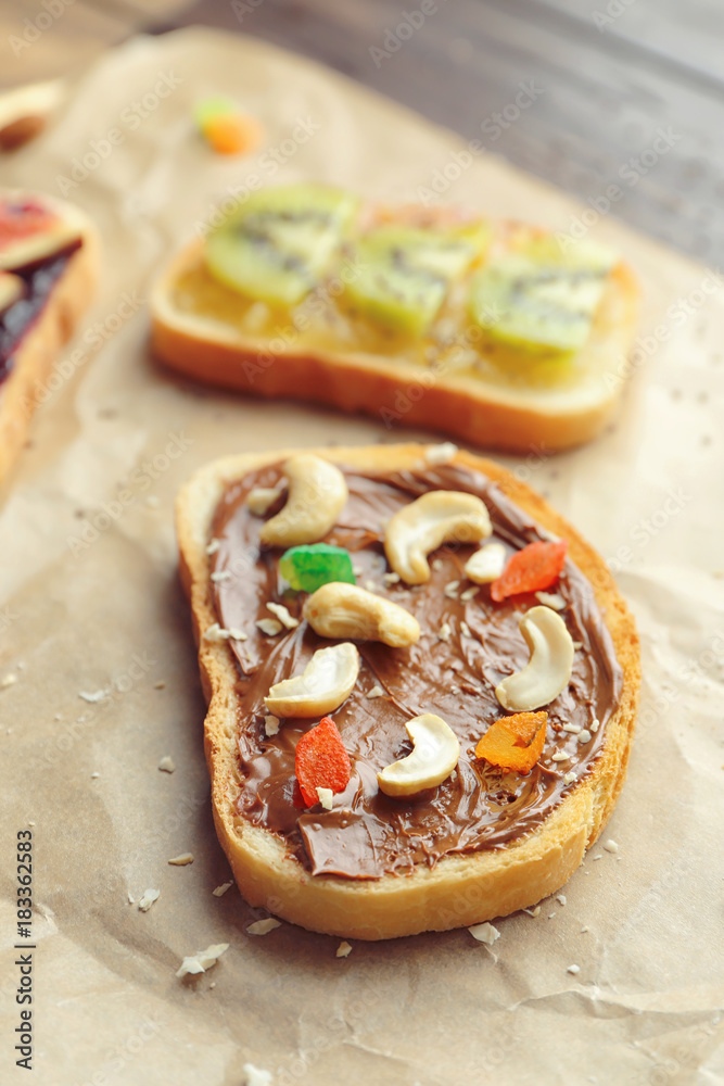 Delicious toast with chocolate paste and nuts on parchment